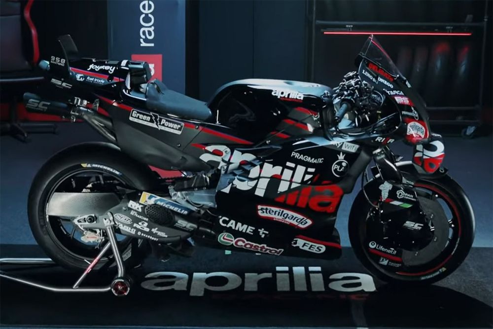 Aprilia RS-GP on the podium with team members celebrating a race result and the rider holding a trophy