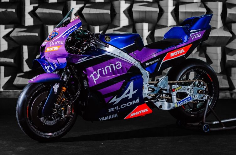 Team engineers and crew gathered around a laptop and bike during a technical briefing trackside