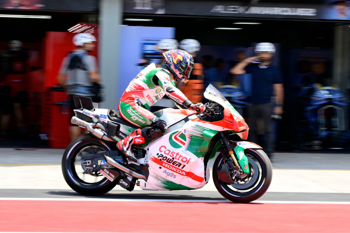 MotoGP rider on a Honda RC213V leaning into heavy braking with front suspension compressed and tire smoke