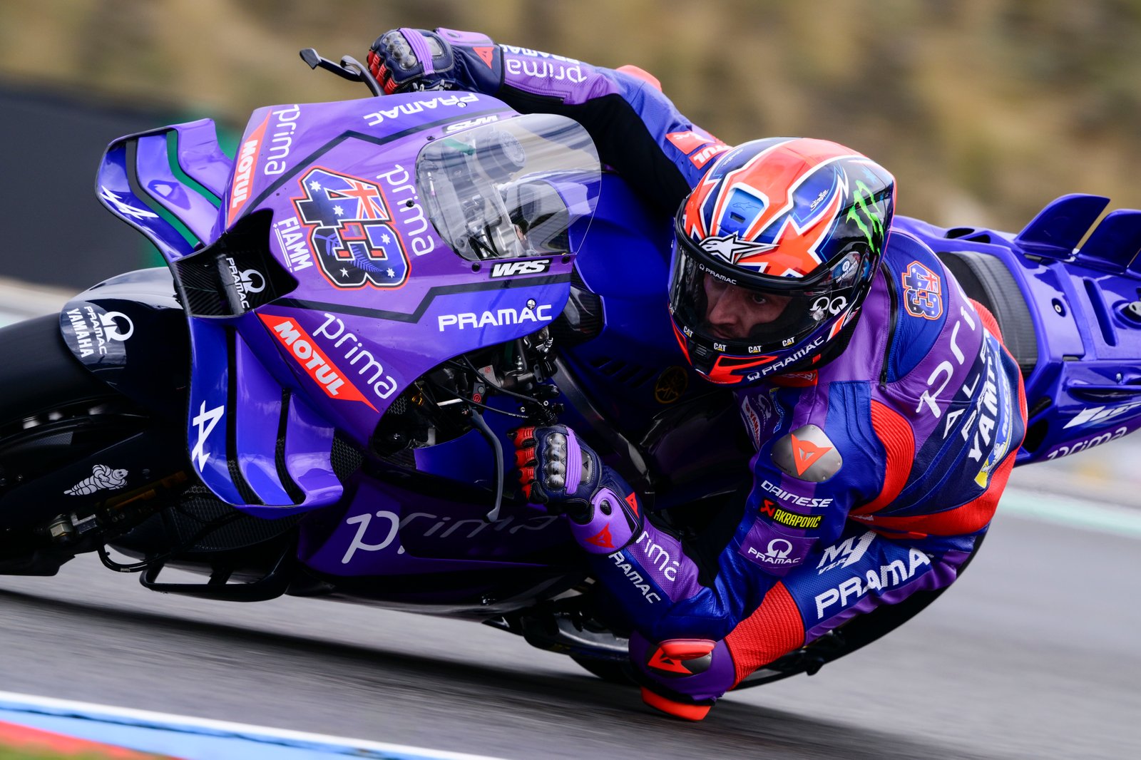 Jack Miller leaning his Ducati aggressively sideways through a tight apex, rear tire sliding slightly as he balances…