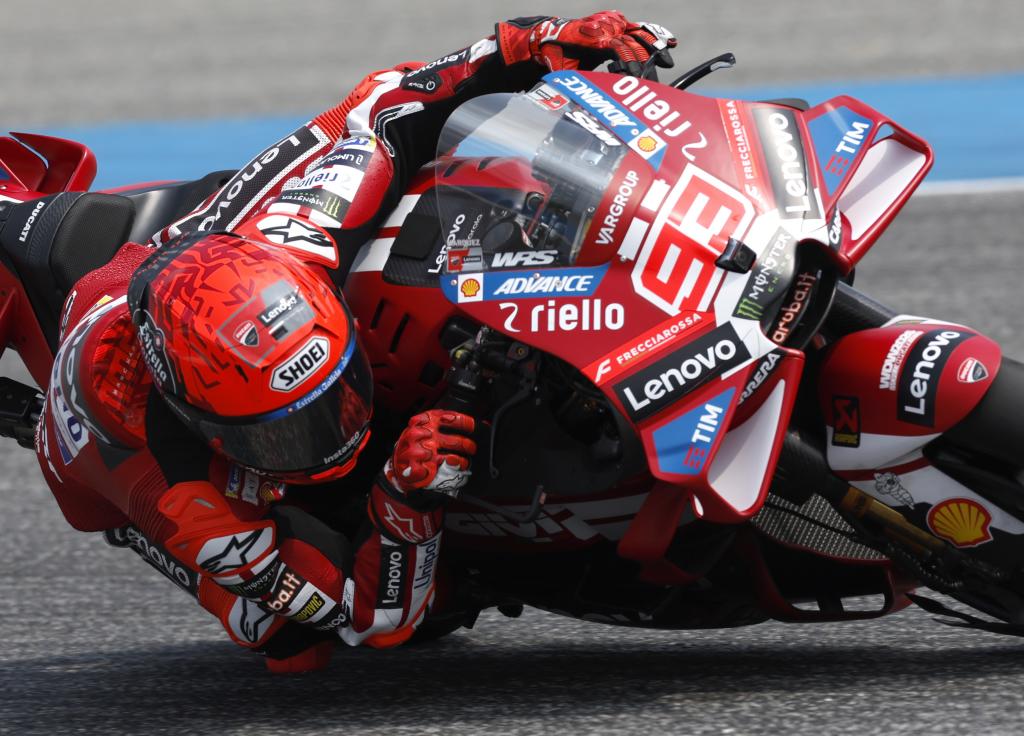 Marc Marquez wearing a Shoei helmet in profile during a corner exit, visor reflecting the track