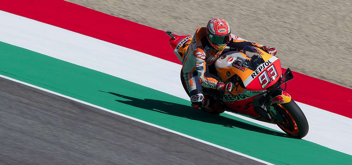 MotoGP rider braking hard into Arrabbiata corner with visible lean and front-wheel compression